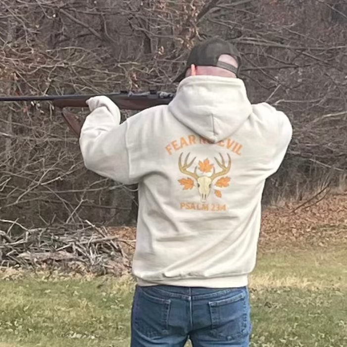 Man wearing a Fear No Evil Psalm 23:4 hoodie while shooting a rifle outdoors, Christian hunting apparel by Rack & River Outdoors.